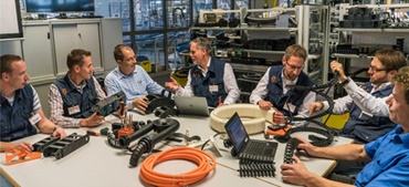 Asztal mellett ülő igus-dolgozók különféle termékekkel